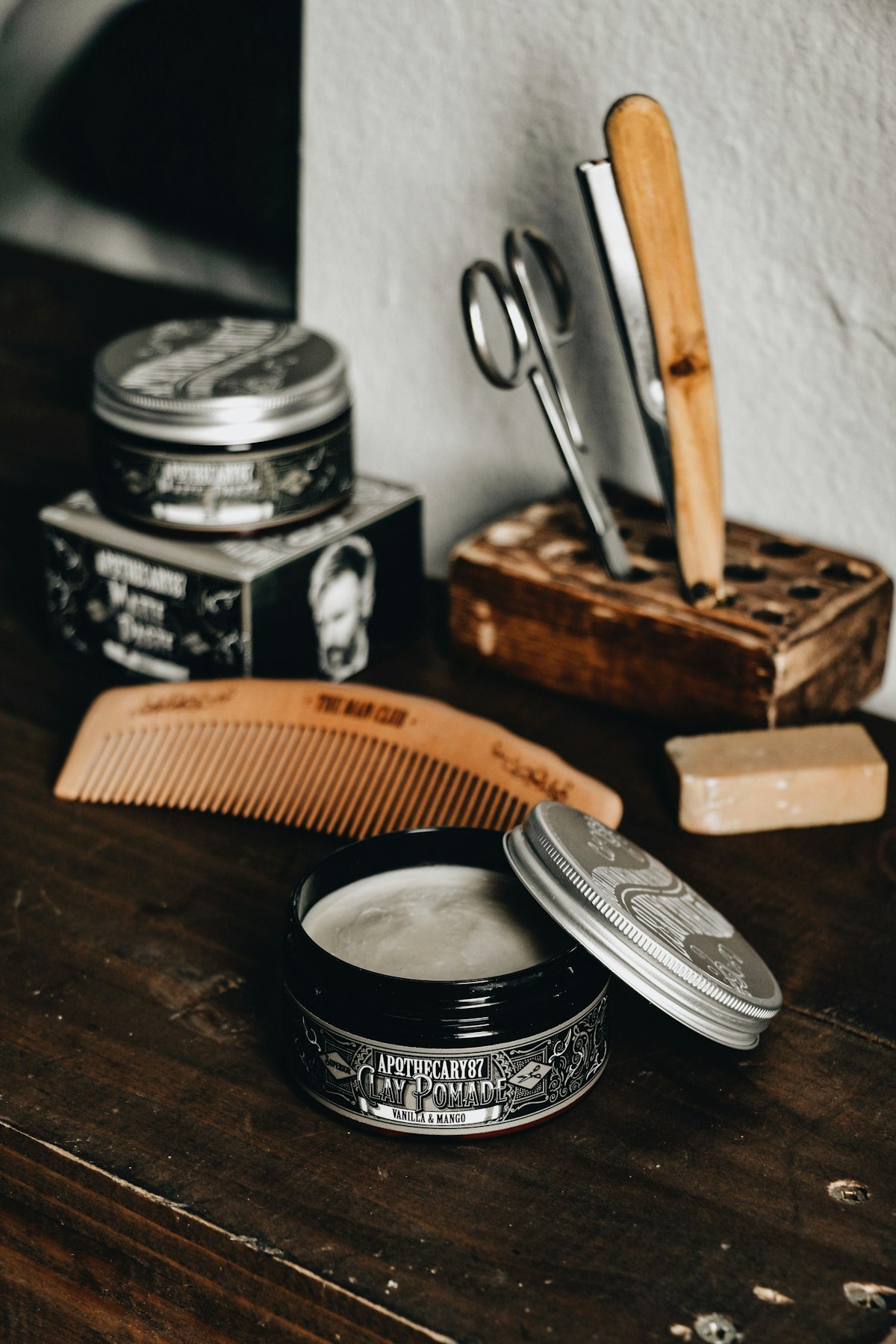 Herramientas de barbero, peine, navaja y pomadas sobre madera
