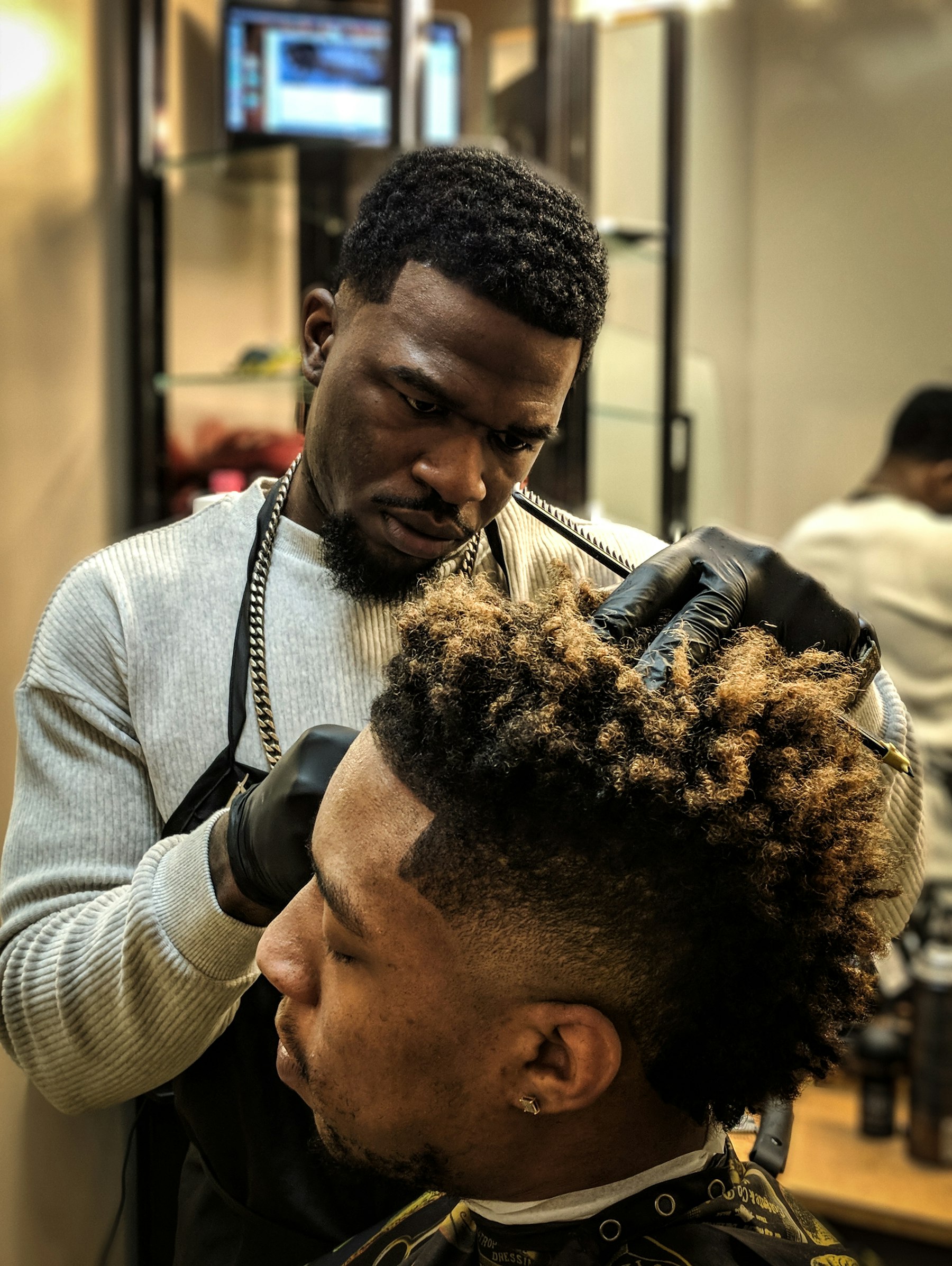 Barbero sectorizando y preparando el cabello del cliente con producto antes del corte